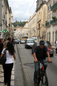 Ciclista se aventura nas ruas de Coimbra, entre a guia, uma tampa de bueiro e os carros