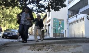 acompanhante e Idosa desviam de buraco na calçada