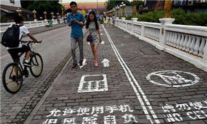 Casal anda na primeira calçada para usar celulares