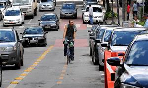 Ciclista fica entre veículos estacionados e o trân