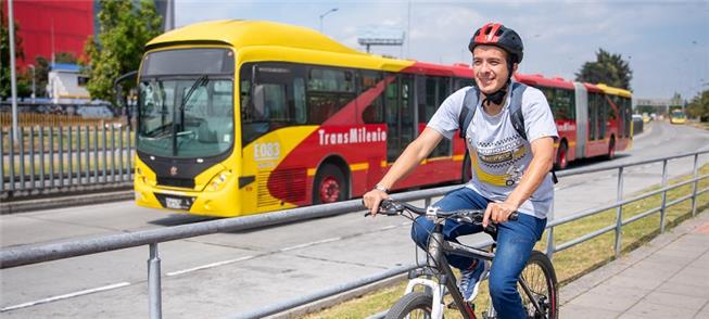 Ciclista pedala ao lado do sistema TransMilenio, e
