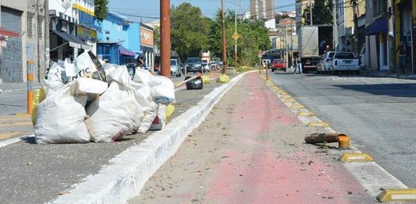 Ciclovia com pintura gasta, lixo e baliza caída na