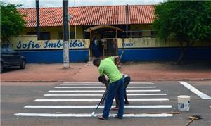 Funcionário e pai de aluno pintando a faixa de ped