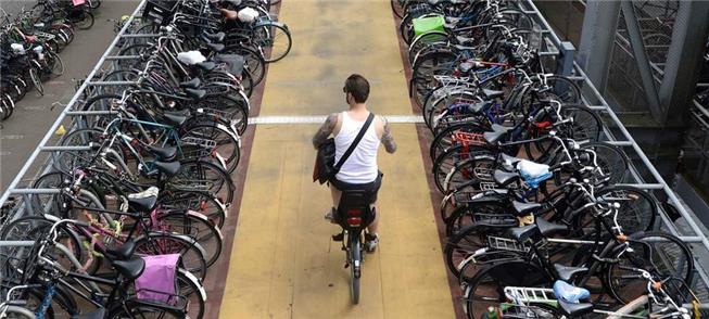 Homem chega ao bicicletário de Amsterdã