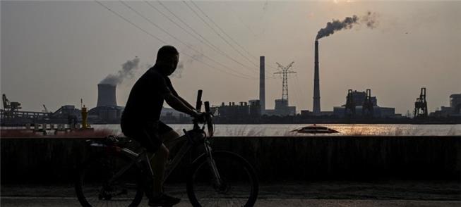 Homem pedala ao longo do rio Huangpu, na China