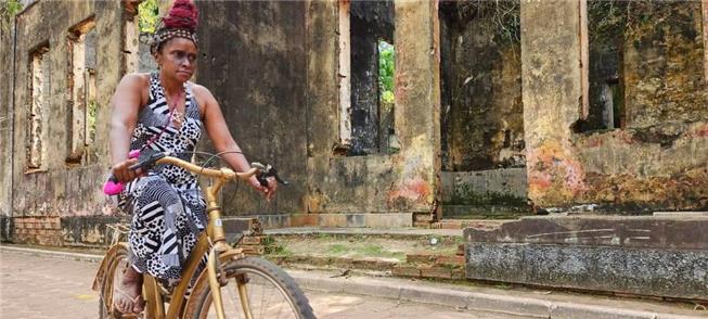Moradora usa bike do projeto Trilha Dourada, em Co