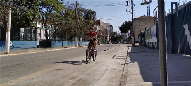 Mulher pedala em ciclovia desgastada por obra, em