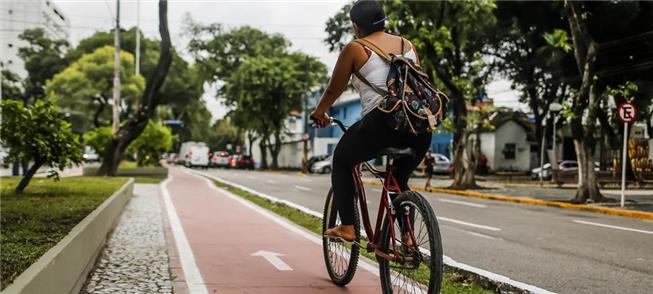 Mulher pedala em ciclovia na cidade do Recife