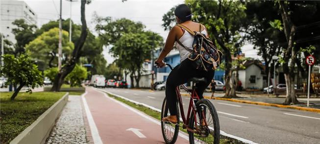 Mulher pedala em ciclovia na cidade do Recife