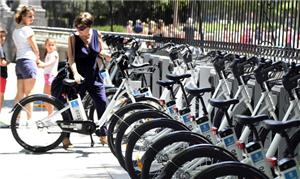 Mulher pega bicicleta em local de aluguel em Madri