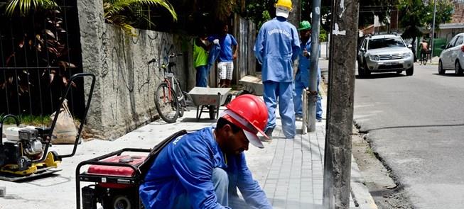 Operário assenta piso intertravado em calçada de R