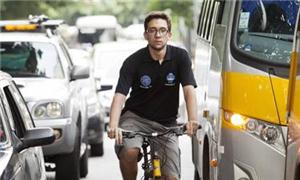 Philipe Moura pedala entre ônibus e carros na rua