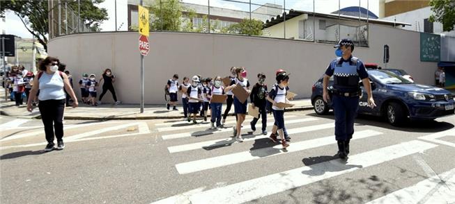 Pranchetas na mão, crianças percorrem a pé ruas de