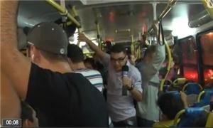 Repórter entrevista passageiros em ônibus cheio
