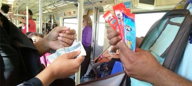 Vendedor atende cliente em carro do metrô de São P